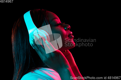 Image of African young woman\'s portrait on dark studio background in neon. Concept of human emotions, facial expression, youth, sales, ad.