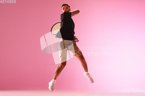 Image of Young caucasian man playing tennis isolated on pink studio background, action and motion concept