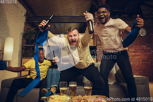 Image of Group of friends watching TV, sport match together. Emotional fans cheering for favourite team, watching on exciting game.