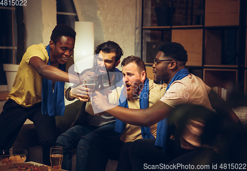 Image of Group of friends watching TV, sport match together. Emotional fans cheering for favourite team, watching on exciting game.