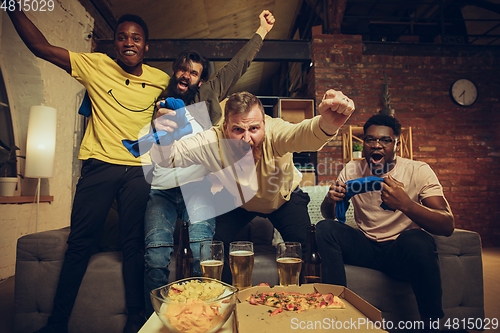 Image of Group of friends watching TV, sport match together. Emotional fans cheering for favourite team, watching on exciting game.