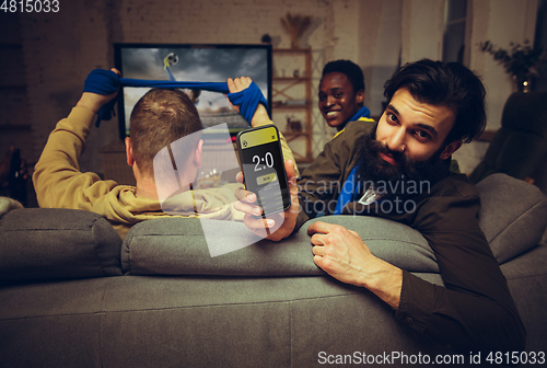 Image of Group of friends watching TV, sport match together. Emotional fans cheering for favourite team, watching on exciting game.