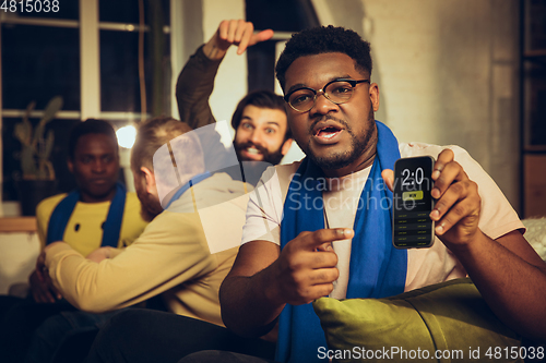 Image of Group of friends watching TV, sport match together. Emotional fans cheering for favourite team, watching on exciting game.