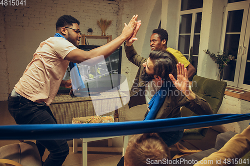 Image of Group of friends watching TV, sport match together. Emotional fans cheering for favourite team, watching on exciting game.