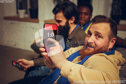 Image of Group of friends watching TV, sport match together. Emotional fans cheering for favourite team, watching on exciting game.