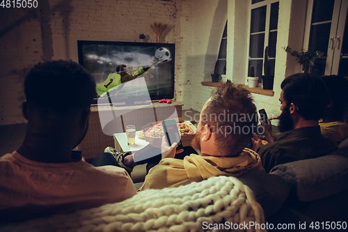 Image of Group of friends watching TV, sport match together. Emotional fans cheering for favourite team, watching on exciting game.