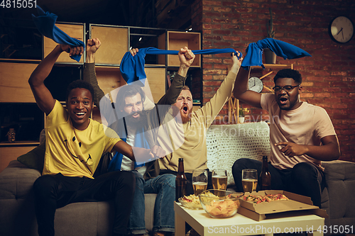 Image of Group of friends watching TV, sport match together. Emotional fans cheering for favourite team, watching on exciting game.