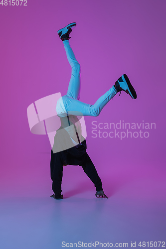 Image of Young stylish man in modern street style outfit isolated on gradient background in neon light. African-american fashionable model in look book, musician performing.