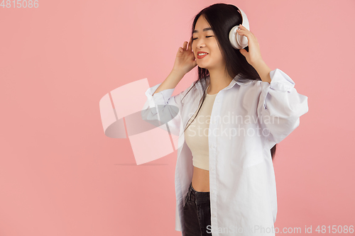 Image of Asian young woman\'s portrait on pink studio background. Concept of human emotions, facial expression, youth, sales, ad.