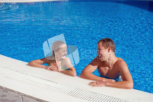 Image of boy and girl having fun in swimming pool