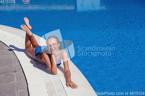 Image of teen girl relaxing near swimming pool