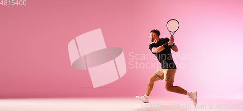 Image of Young caucasian man playing tennis isolated on pink studio background, action and motion concept