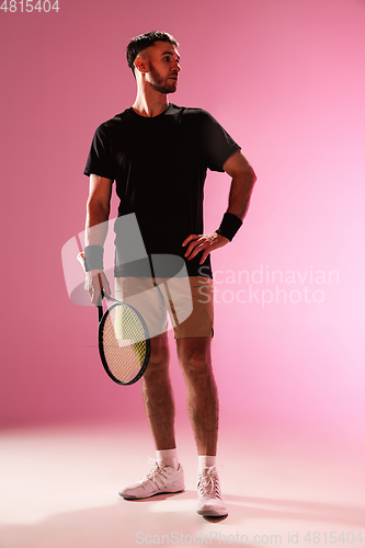 Image of Young caucasian man playing tennis isolated on pink studio background, action and motion concept