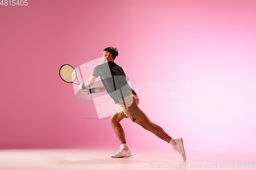 Image of Young caucasian man playing tennis isolated on pink studio background, action and motion concept