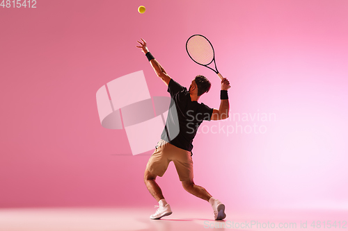 Image of Young caucasian man playing tennis isolated on pink studio background, action and motion concept