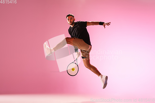 Image of Young caucasian man playing tennis isolated on pink studio background, action and motion concept