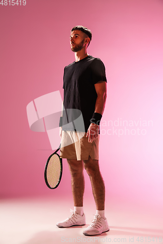 Image of Young caucasian man playing tennis isolated on pink studio background, action and motion concept