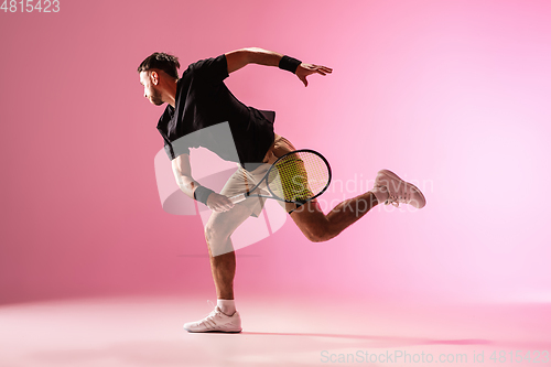 Image of Young caucasian man playing tennis isolated on pink studio background, action and motion concept