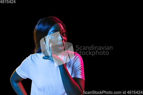 Image of African young woman\'s portrait on dark studio background in neon. Concept of human emotions, facial expression, youth, sales, ad.