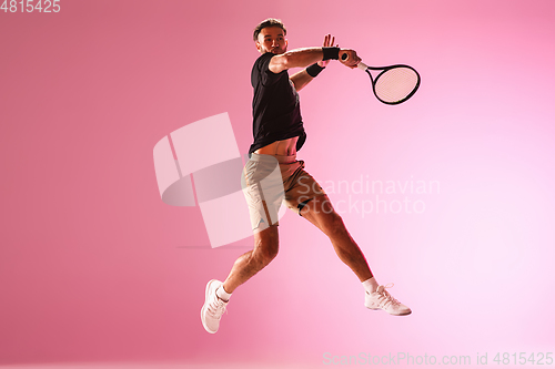 Image of Young caucasian man playing tennis isolated on pink studio background, action and motion concept