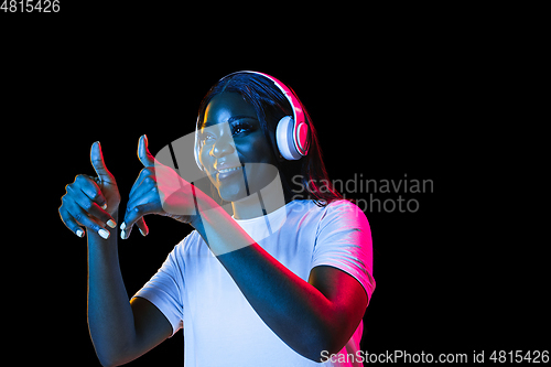Image of African young woman\'s portrait on dark studio background in neon. Concept of human emotions, facial expression, youth, sales, ad.