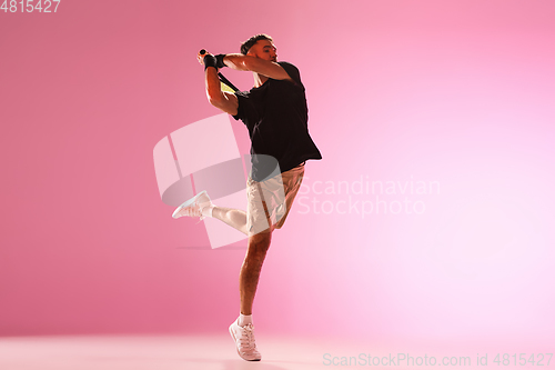 Image of Young caucasian man playing tennis isolated on pink studio background, action and motion concept