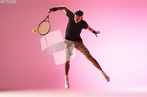 Image of Young caucasian man playing tennis isolated on pink studio background, action and motion concept