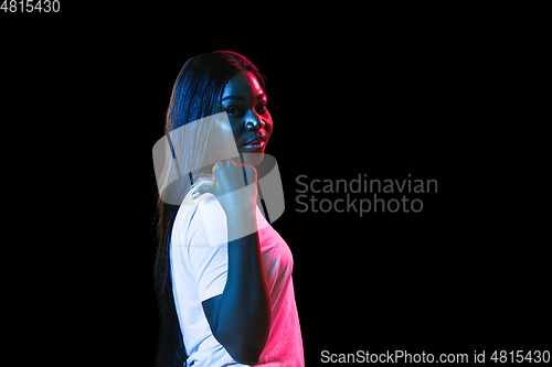 Image of African young woman\'s portrait on dark studio background in neon. Concept of human emotions, facial expression, youth, sales, ad.