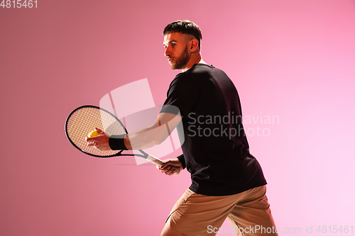 Image of Young caucasian man playing tennis isolated on pink studio background, action and motion concept