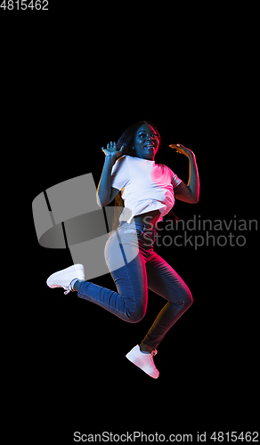 Image of African young woman\'s portrait on dark studio background in neon. Concept of human emotions, facial expression, youth, sales, ad.