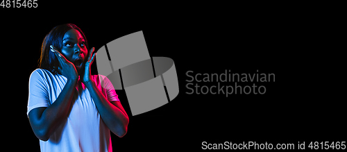 Image of African young woman\'s portrait on dark studio background in neon. Concept of human emotions, facial expression, youth, sales, ad.