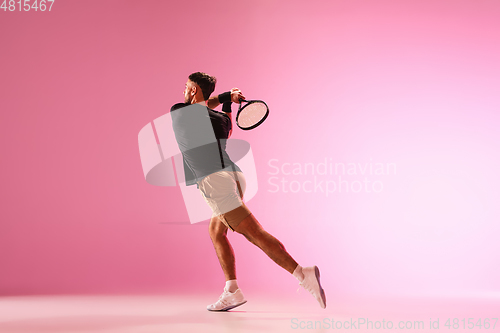 Image of Young caucasian man playing tennis isolated on pink studio background, action and motion concept