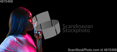 Image of African young woman\'s portrait on dark studio background in neon. Concept of human emotions, facial expression, youth, sales, ad.