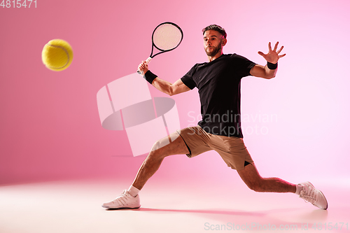 Image of Young caucasian man playing tennis isolated on pink studio background, action and motion concept