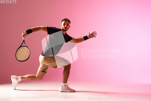 Image of Young caucasian man playing tennis isolated on pink studio background, action and motion concept