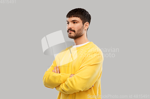 Image of young man in yellow sweatshirt with crossed arms