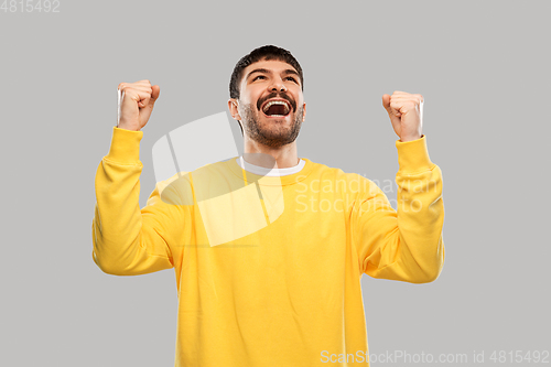 Image of happy man in yellow sweatshirt celebrating victory