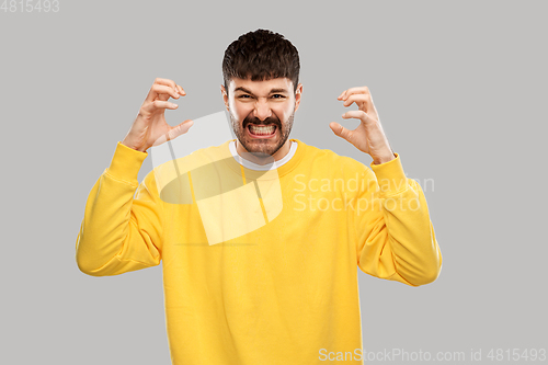 Image of angry young man in yellow sweatshirt over grey