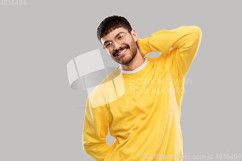 Image of smiling young man in glasses and yellow sweatshirt