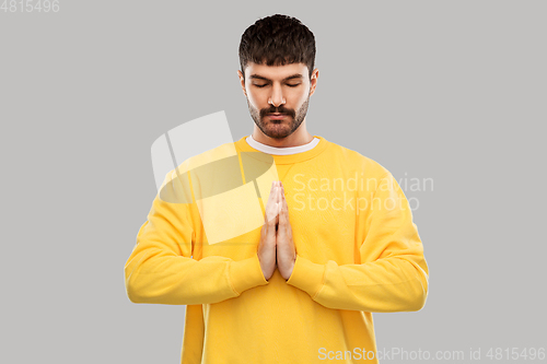 Image of man in yellow sweatshirt meditating or praying