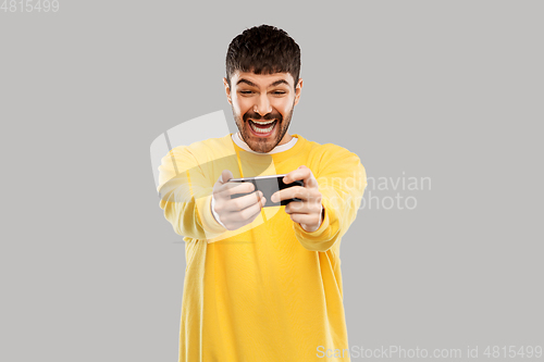 Image of happy laughing young man with smartphone