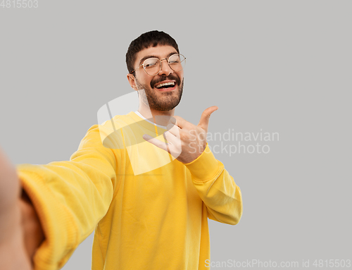 Image of happy young man in yellow sweatshirt making selfie