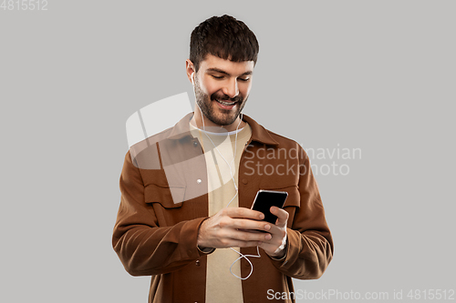 Image of smiling young man with earphones and smartphone