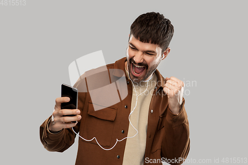 Image of smiling young man with earphones and smartphone