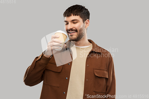 Image of happy young man drinking coffee from takeaway cup