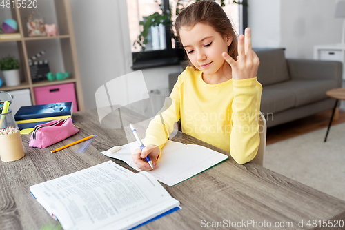 Image of student girl with book writing to notebook at home