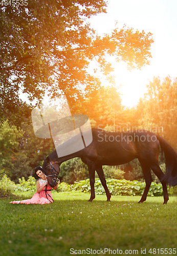 Image of beautiful girl in dress with horse