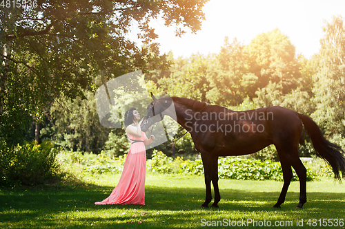 Image of beautiful girl in dress with horse