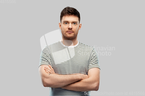 Image of young man in striped t-shirt with crossed arms