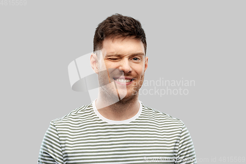 Image of smiling young man in striped t-shirt winking